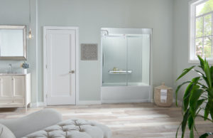 A spacious bathroom with a chair in the foreground and a tub/shower combo with glass doors.