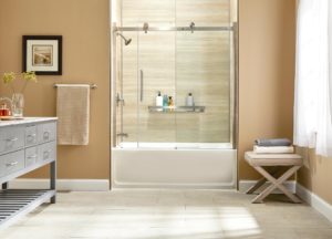 An updated bathroom with beige tile floors and a tub and shower combination with a sliding glass door.