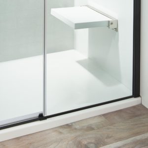 A close-up image of a glass shower door with a black frame.