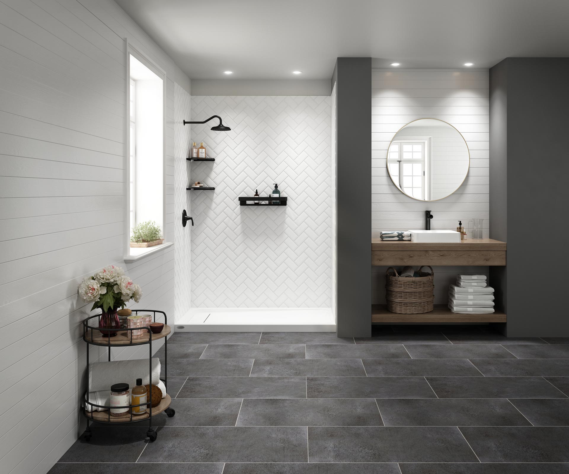 A beautiful bathroom with dark gray tile flooring, a wood vanity, and a shower that has a white herringbone tile wall system.