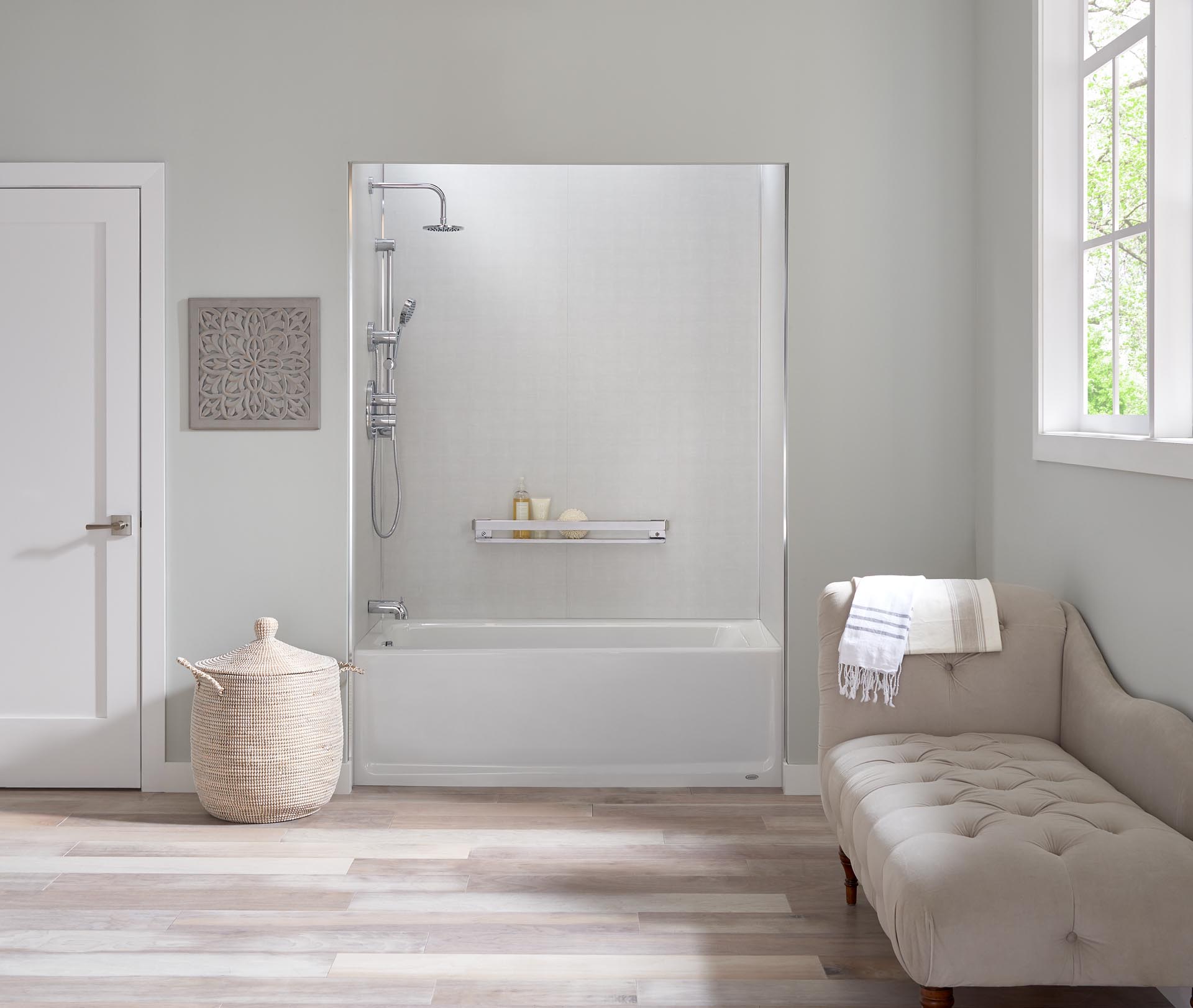 A beautiful bathroom with a light gray fainting sofa and a shower and bathtub combination.