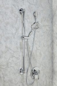 A detachable showerhead mounted to a textured shower wall.