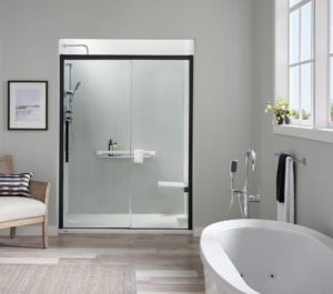 A beautiful bathroom has a freestanding bathtub and a walk-in shower with a black-framed glass door.